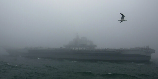Schemenhaft ist im Nebel ein Flugzeugträger zu erkennen