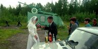 Ein Hochzeitspaar stößt vor einem Kriegerdenkmal mit der Verwandschaft gemeinsam