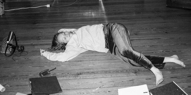 Schwarz-weiß-Foto einer Frau, die auf dem Boden neben Aktenordnern liegt
