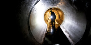 Arbeiter mit Taschenlampe in Kanalisation