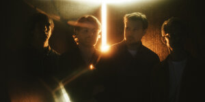 Foto der vier Band-Mitglieder von Django Django in diffusem Licht