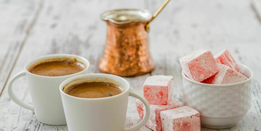 Eine Mokkakanne auf einem Holztisch, daneben Tassen und türkischer Honig