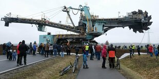 Schaulustige beobachten, wie ein 345 Tonnen schwerer Schaufelradbagger die Bundesstraße 176 zwischen Groitzsch und Neukieritzsch (Kreis Leipzig) überquert. Der 12,5 Meter hohe, 43 Meter lange und 12 Meter breite Bagger werde künftig im Abbaufeld Peres ein