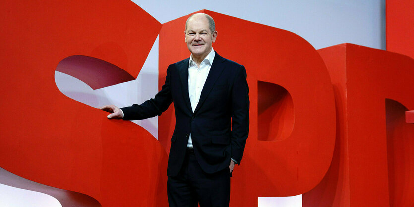 Olaf Scholz steht vor einem lebensgroßen SPD-Schriftzug