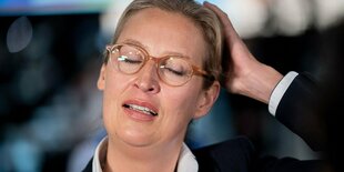 Der Kopf von Alice Weidel. Sie hält sich die linke Hand an den Hinterkopf und hält die Augen geschlossn