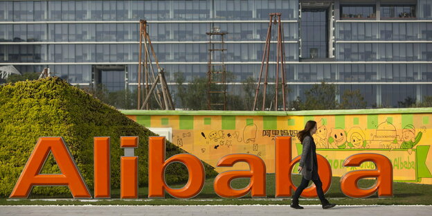Eine Frau an einem großen Alibaba-Firmenschild vorbei