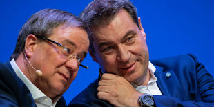 Armin Laschet und Markus Söder nebeneinander auf einem Podium, die Köpfe zueinander geneigt