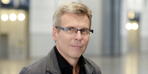 Portrait von Jörg Magenau, ein Mann mittleren Alters mit graumelierten Haaren und eckiger Brille