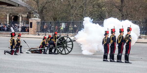Mitglieder der britischen Armee stehen neben einer Kanone, aus der weißer Rauch kommt