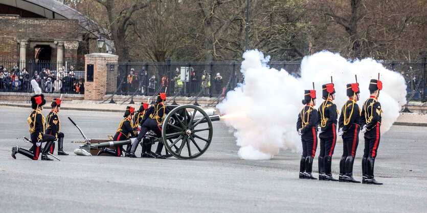 Mitglieder der britischen Armee stehen neben einer Kanone, aus der weißer Rauch kommt