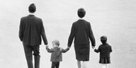 Schwarz-Weiß Foto einer Familie ,Vater, Mutter mit zwei Kindern, die Familie Hand in Hand laufen - Aufnahme von hinten