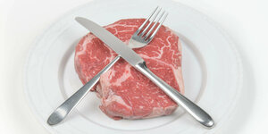 Das Bild zeigt einen Telle rmit einem rohen Steak, darüber formen Messer und Gabel ein X.