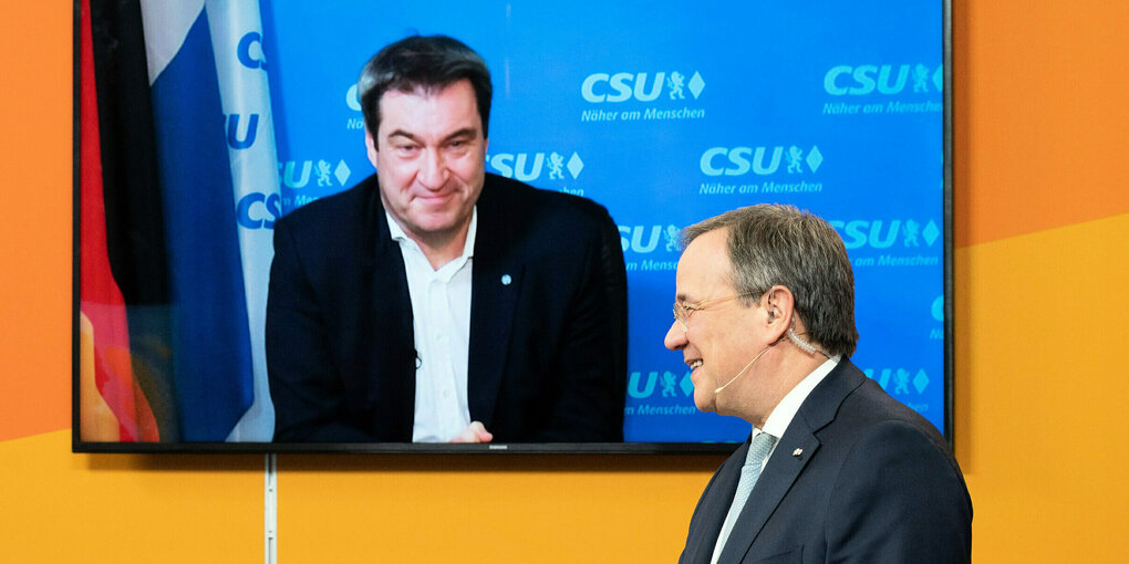 Laschet vor einem Bildschirm, in dem Söder zu sehen ist.