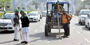 Zwei Bauern stehen auf einer Straße, daneben ein Traktor