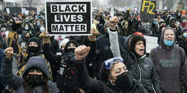 Menschen demonstrieren mit einem "Black Lives Matter"-Schild