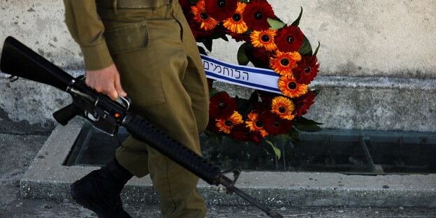 Ein Soldat mit Waffe und Gedenkkranz.