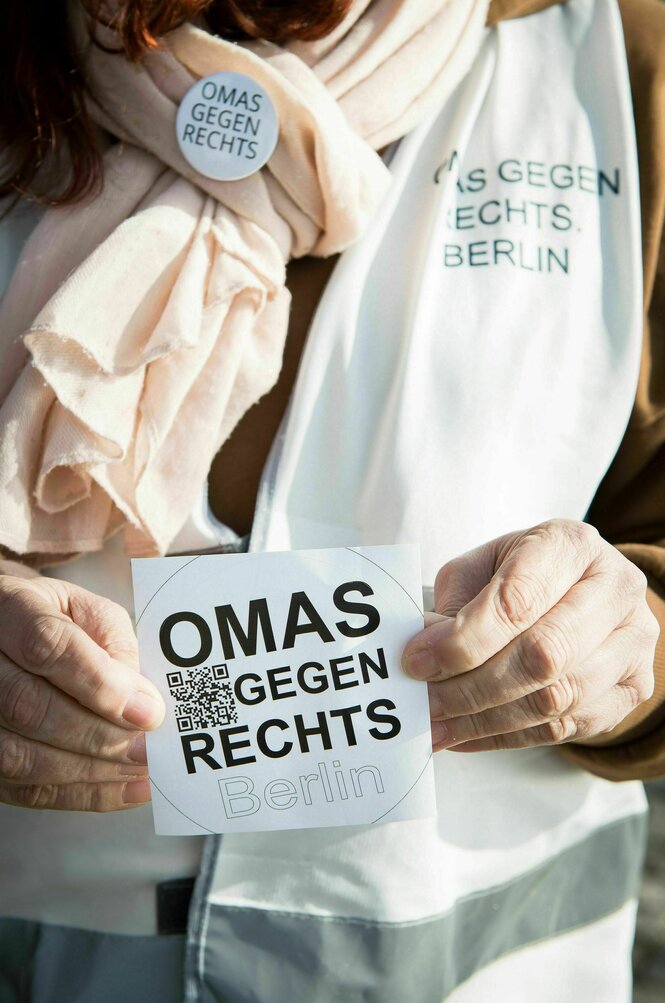 Ein Aufkleber im Großaufnahme, von zwei Fingern gehalten, darauf der Schriftzug "Omas gegen Rechts"