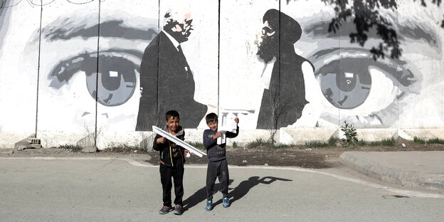 Zwei Jungen spielen vor einem Graffiti in Kabul