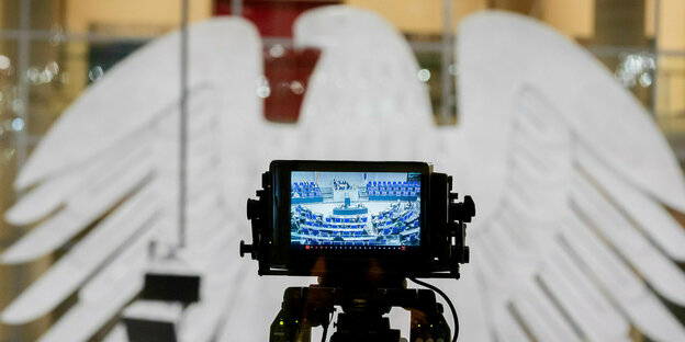 Bundesadler im Bundestag. Davor eine TV-Kamera.
