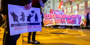 Im Vordergrund ein Schild: "Berlin gegen Nazis. Wir sind viele", im Hintergrund eine Demo