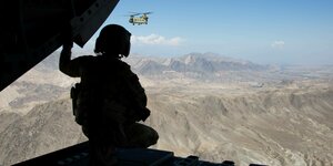 Ein Soldat beobachtet einen Hubschrauber, im Hintergrund die afghanischen Berge
