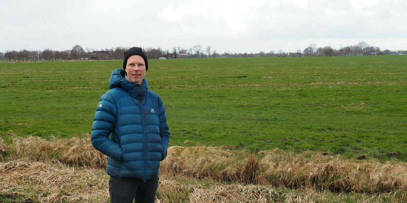 Florian Knöppler steht vor einem grünen Feld.