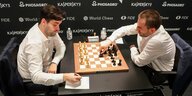 Zwei Schachprofis vor dem Brett, der eine notiert den Spielzug