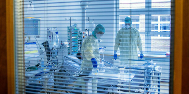Mediziner und Pfleger versorgen einen an Covid-19 erkrankten Patienten in einem Zimmer des besonders geschützten Teils der Intensivstation des Universitätsklinikums Greifswald