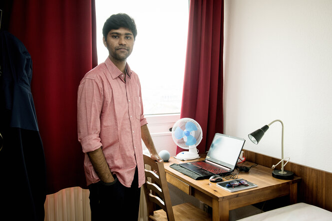 Masterstudent Nikhil Deshpande steht vor seinem Schreibtisch in seinem Wohnheimzimmer, er kam aus Indien zum Studium nach Berlin