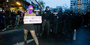 Demonstrantin mit Schild vor Polizisten.