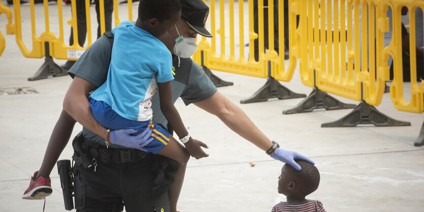 Ein Beamter der Guardia Civil trägt ein Flüchtlingskind in einem Sportzentrum in Los Barrios, Südspanien