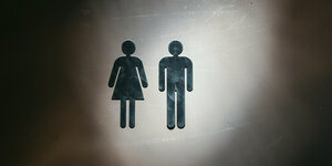 Symbole für Frau und Mann in einem Lichtkegel