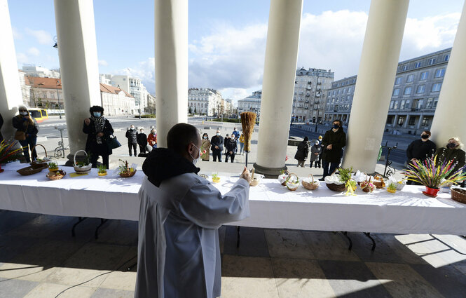 Ein Priester segnet Osterkörbe, die Gemeindemitglieder vor die St. Alexandra Kirche gebracht haben