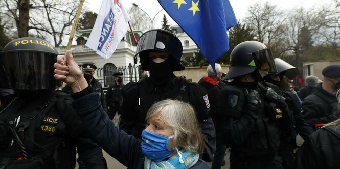 Eine Demonstrantin hält die EU-Flagge vor der russischen Botschaft in Prag hoch. Neben ihr ein polizeiliches Aufgebot