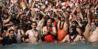 Indische Männer drängen sich am Ufer und im Wasser.