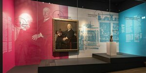 Blick in den Ausstellungsraum mit dem Porträt von Karl von Linden. Der Raum ist In rotes und blaues Licht getaucht.