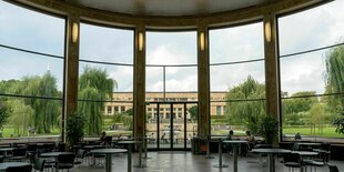 Blick durch eine Fenster auf einen park und ein anderes Gebäude.