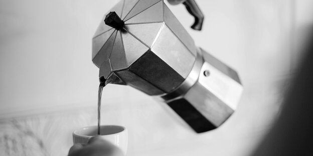 Aus einer Espressokanne wird Espresso in eine Tasse gegossen.