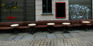 Leere Tische und Bänke stehen vor einer Kneipe in der Altstadt von Halle/Saale