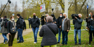 Eine Frau der Initiative "Querdenken" steht mit einem Schild vor Journalisten in Frankfurt am Main