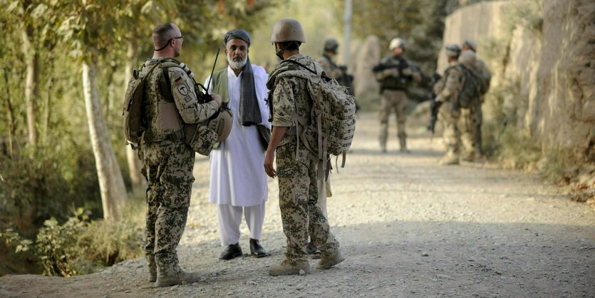 Ein Bundeswehrsoldat (l) und ein Dolmetscher sprechen nahe Kundus mit einem Mann