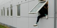 Eine Person klettert aus einem Fenster.