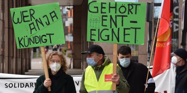 Drei Personen mit Transparenten demonstrieren für die Betriebsrätin