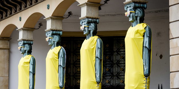 mit gelben Trikots geschmückte Säulen in Menschenform