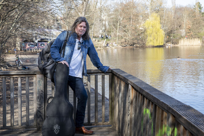 Der Musiker Torsten Kelling an einem Seeufer an einem Zaun gelehnt stehend