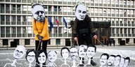 Demonstranten mit Masken von Politikern.