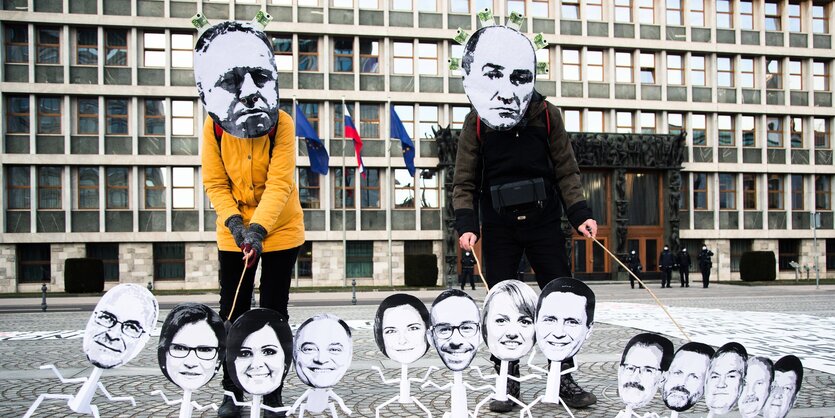 Demonstranten mit Masken von Politikern.