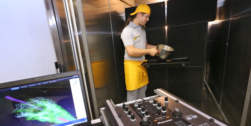 Ein Mann mit gelber Schürze hält eine Backschüssel in der Hand