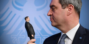 Markus Söder hat eine 3D Figur von sich in der Hand und schaut diese an