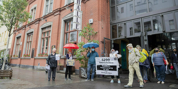 Menschen protestieren vor der Markthalle Neun in Kreuzberg für den Erhalt von Grundversorgung